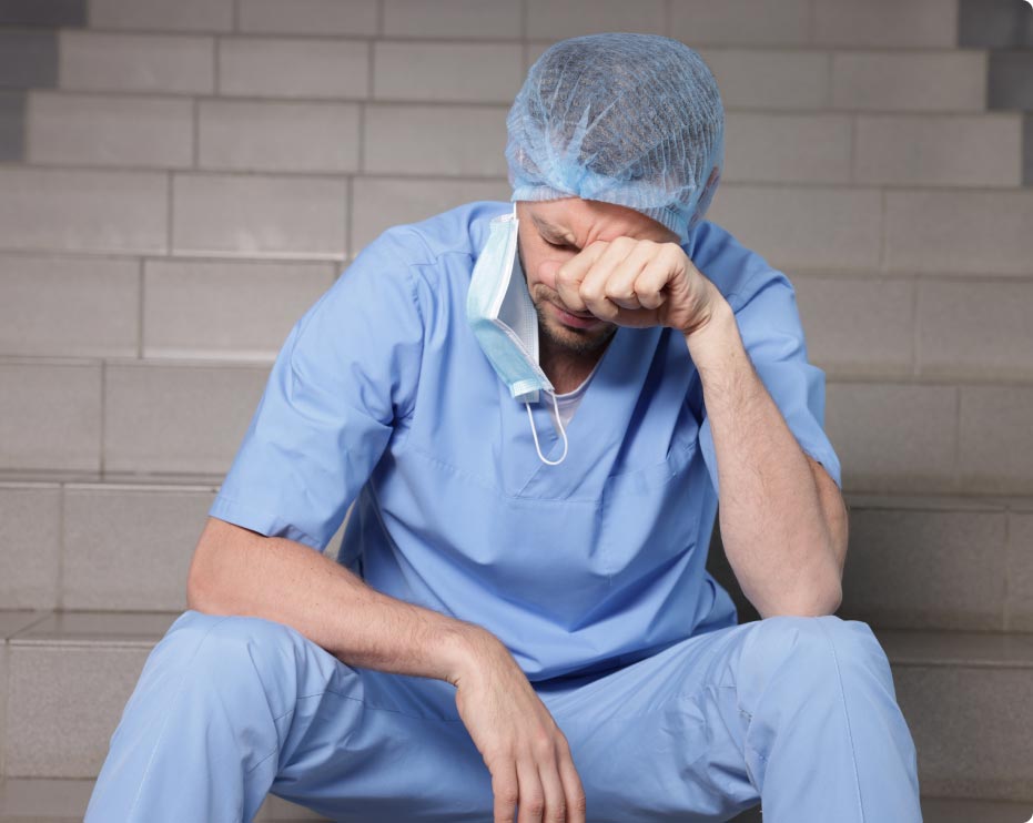tired male doctor sitting on stairs holding his head